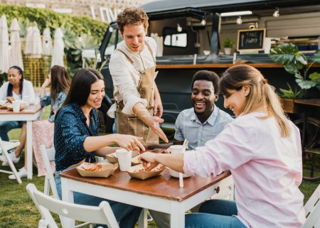 Photo for Multiracial people having fun eating at food truck outdoor - Focus on left girl face - Royalty Free Image