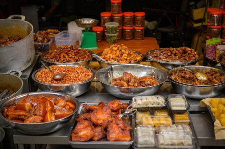 Téléchargez les photos : High angle pieces of smoked pork in various metal and plastic containers placed on stall in local bazaar of Vietnam - en image libre de droit
