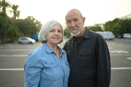Photo for Positive senior man and woman with gray hair smiling and looking at camera while standing on city street - Royalty Free Image