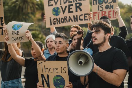 Foto de Grupo de manifestantes multiétnicos con pancartas y hombre con altavoz que representa un problema ecológico durante la manifestación en la calle - Imagen libre de derechos