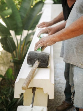 Téléchargez les photos : De dessus de maçon mâle anonyme vintage utilisant un marteau tout en travaillant sur une rampe en plâtre - en image libre de droit