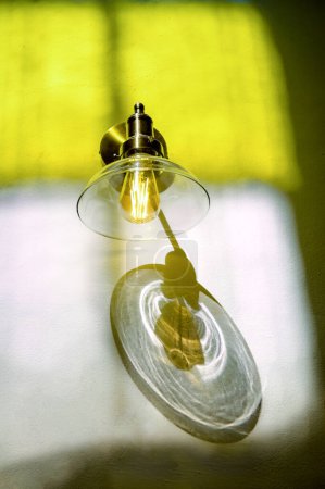Photo for Low angle of shining lamp with transparent glass shade hanging on wall in selective focus - Royalty Free Image
