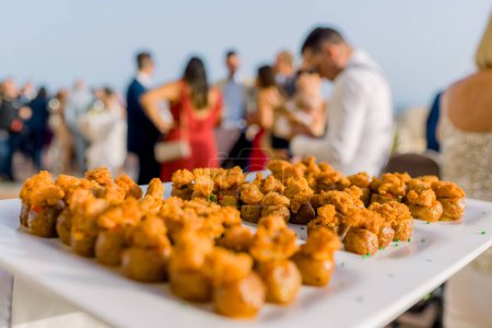 Téléchargez les photos : Délicieux morceaux de poulet rôtis servis sur une assiette blanche sur une table de banquet lors d'un événement festif contre une foule floue dans la rue - en image libre de droit