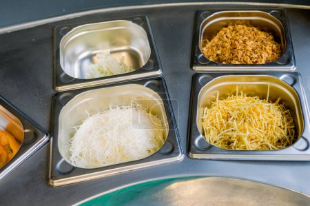 Photo for From above of salad and grated cheese with onion fries and straw potatoes placed in metal boxes in counter - Royalty Free Image