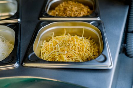 Photo for High angle of straw potatoes in container placed near grated cheese and onion fries in fast food restaurant - Royalty Free Image