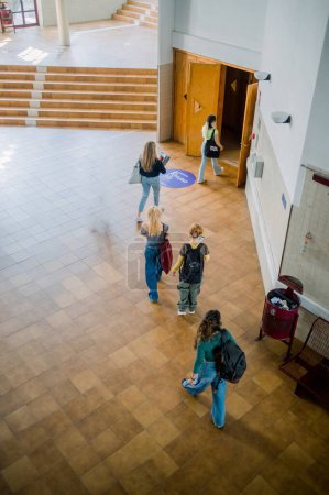 Téléchargez les photos : D'en haut des étudiants anonymes marchant sur le sol dans le hall spacieux tout en entrant par la porte pour la conférence - en image libre de droit