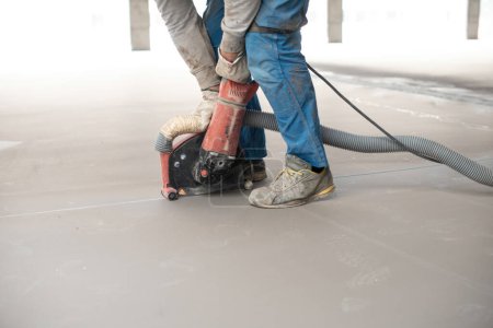 Photo for Side view of crop unrecognizable male master in workwear and gloves screeding and leveling concrete floor with machine during construction works - Royalty Free Image