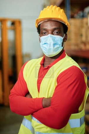 Photo for Portrait of an African worker inside a warehouse with safety mask - Focus on the mans eyes - Royalty Free Image