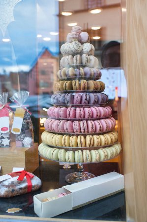 Photo for Christmas tree-shaped macaroon cakes through the glass in the window of a bakery shop - Royalty Free Image