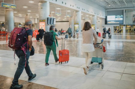 Téléchargez les photos : Vue arrière des voyageurs anonymes en avion en vêtements décontractés avec sacs à dos et bagages marchant dans le hall de départ lumineux coloré de l'aéroport - en image libre de droit