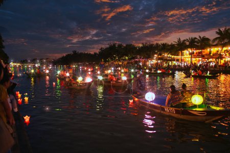 Téléchargez les photos : Vue latérale de personnes méconnaissables assis sur le bateau et flottant sur l'eau calme dans la soirée - en image libre de droit
