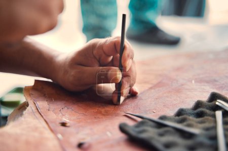 Foto de Cortar la mano de artesano cortando pieza de cuero con borde afilado mientras trabaja en un taller profesional - Imagen libre de derechos