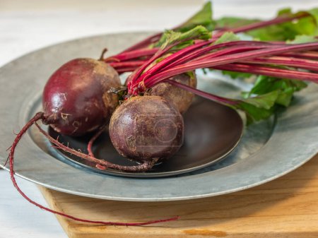 Photo for Beets with bright red stems and green leaves ready to be peeled and sliced. - Royalty Free Image