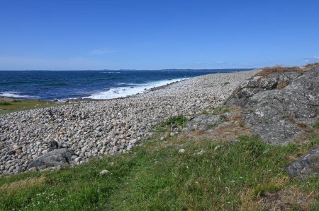Foto de Esta playa de grandes guijarros con rocas que rodan en el oleaje se encuentra en Brunlanes, Noruega. - Imagen libre de derechos