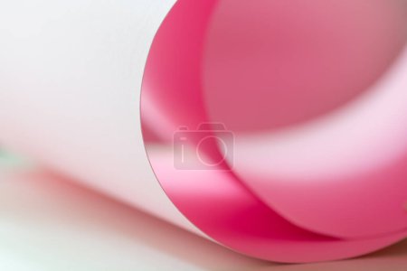 A roll of pink cardstock paper on a desk.