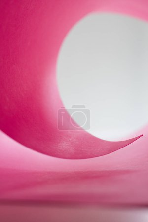 The corner of a roll of thick paper forming a circle against a bright white background.