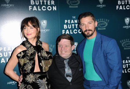 Foto de Dakota Johnson, Zack Gottsagen y Shia LaBeouf en el estreno en Los Ángeles de 'The Peanut Butter Falcon' celebrado en ArcLight Cinemas en Hollywood, EE.UU. el 1 de agosto de 2019. - Imagen libre de derechos