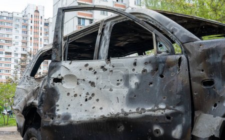 Foto de Un coche quemado con agujeros de metralla frente a una casa con ventanas rotas después del mayor ataque de misiles de Rusia contra Kiev, el concepto de la guerra de Rusia contra Ucrania, el genocidio del pueblo ucraniano - Imagen libre de derechos