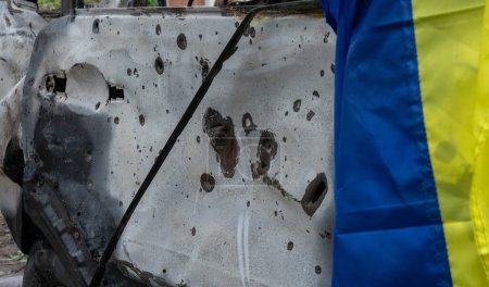 Téléchargez les photos : Bullet and shrapnel holes in the civil transport hull and the Ukrainian flag on it after the largest rocket attack on Kiev, the concept of Russia's war against Ukraine, background and texture - en image libre de droit