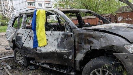 Foto de Bandera de Ucrania en un coche quemado con agujeros de metralla en el lugar de la explosión después del mayor ataque de misiles nocturnos en la capital, el dolor, el concepto de la guerra de Rusia - Imagen libre de derechos