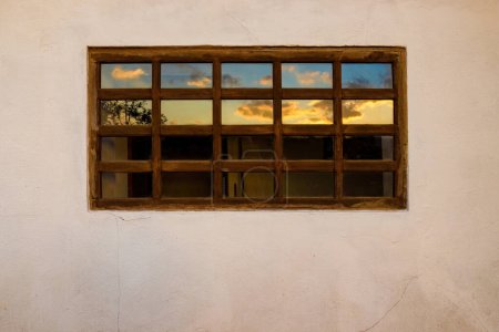 Foto de Los hermosos colores del resplandor reflejados en una ventana de paneles de madera, en una granja de casas en las montañas andinas orientales del centro de Colombia. - Imagen libre de derechos