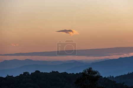 Una nube muy pequeña flota en el horizonte, en un hermoso atardecer sobre las montañas andinas orientales del centro de Colombia.