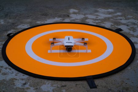 Dron blanco preparándose para despegar en la plataforma del dron. El dron blanco está en el helipuerto naranja. La última tecnología. Pasatiempos y ocio. Enfoque selectivo. Disparo de larga exposición. Disparo en lente Macro