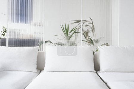 Frontansicht auf zeitgenössisches Sofa und Kissen aus hellem Textil im Wohnzimmer mit Schiebetür-Trennwand, Raumaufteilung zu Hause, Bereich zum Entspannen