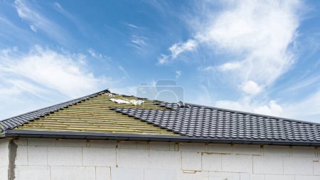 Téléchargez les photos : Construction de la maison et du toit avec cadre en bois recouvert de tuiles gris foncé chevauchement, processus inachevé - en image libre de droit