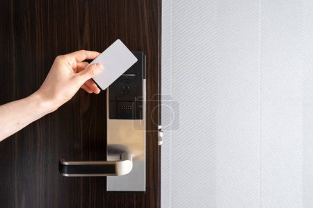 Foto de Recortado tiro de mano femenina usando tarjeta de llave sin contacto de plástico para abrir la puerta de la habitación de hotel, cerradura inteligente, tecnología inalámbrica - Imagen libre de derechos
