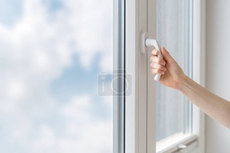 Foto de Tiro recortado de mango de mano femenina y cerrar la ventana de pvc de doble acristalamiento con marco blanco instalado en la casa, proteger la habitación del ruido al aire libre - Imagen libre de derechos