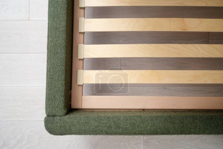 Foto de Vista superior de la base de madera con lamelas en cama moderna con tapicería verde en el dormitorio, primer plano - Imagen libre de derechos