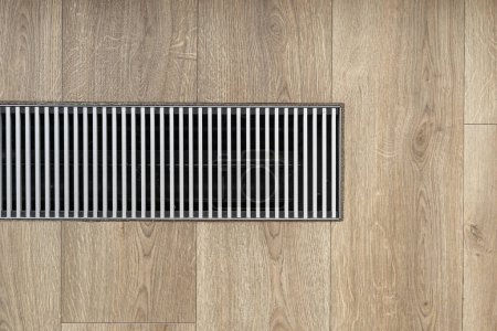 Photo for Close up of underfloor heating system at home. Flat lay with ventilation grill on laminate. Maintaining a favorable microclimate in room. Air conditioning in apartment. - Royalty Free Image