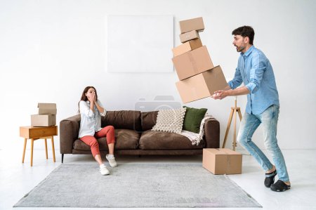 Relocation concept. Shocked young adult man and scared woman move in new flat together, dropping cardboard boxes, looking how package fall on floor, carpet