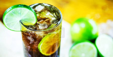Photo for Cuba Libre cocktail with lime, ice, mint and tray on wooden table - Royalty Free Image