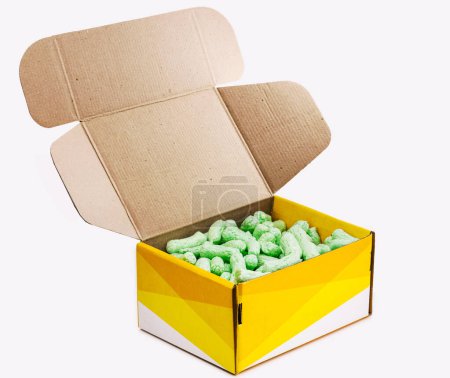 Téléchargez les photos : Boîte d'emballage avec des flocons de polystyrène, arachide biodégradable pour l'emballage. fond blanc isolé - en image libre de droit