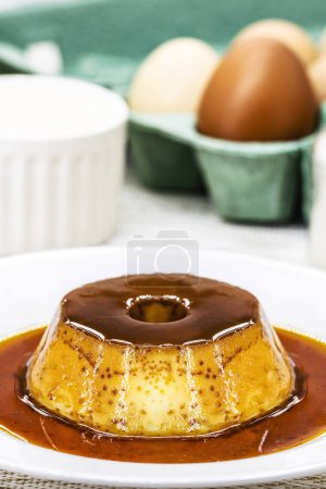 Téléchargez les photos : Small condensed milk pudding, with ingredients in the background, eggs, sugar, cinnamon, caramel and condensed milk, Homemade sweet recipe. - en image libre de droit