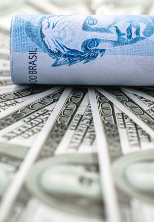 Detail eines Hundert-Reais-Scheins umgeben von 100-Dollar-Scheinen, Konzept der Finanzkrise zwischen Brasilien und den Vereinigten Staaten