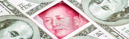 Yuan-Banknote, umgeben von 100-Dollar-Scheinen. Konzept des amerikanischen Marktprotektionismus