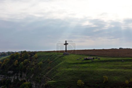 Téléchargez les photos : Easter. There is a cross on a green hill. It is illuminated by the sun's rays from the open sky above it - en image libre de droit