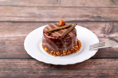 Frische leckere Schokoladenkuchen auf Teller mit Gabel auf Holzuntergrund. Karamellglasur und Dekoration verleihen Reiz und Lust