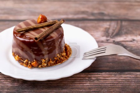 Frische leckere Schokoladenkuchen auf Teller mit Gabel auf Holzgrund in Großaufnahme. Karamellglasur und Dekoration verleihen Reiz und Lust