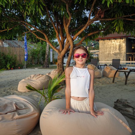 Portrait of a young smiling girl in a white dress and sunglasses on the beach. Thailand, hotel, Travel destinations