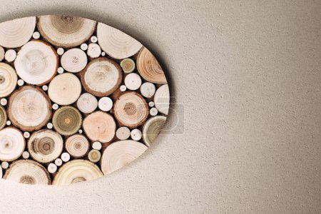Background for design. Wooden stand made of round wood cuts on beige concrete background. Top view