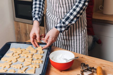 Foto de Cierra las manos de los hombres en la cocina haciendo galletas con cortador de galletas en forma de hombrecito, duendes y estrellas. Vista frontal - Imagen libre de derechos