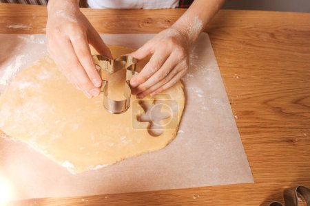 Foto de Cierre las manos de los niños en la cocina haciendo galletas con cortador de galletas en forma de hombrecito. Vista superior - Imagen libre de derechos