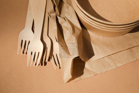 Téléchargez les photos : Ensemble d'ustensiles en papier et de couverts en bois sur fond brun. Concept écologique, zéro déchet. Vue du dessus - en image libre de droit