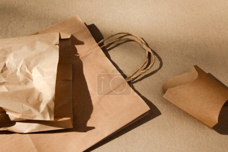 Téléchargez les photos : Ensemble de sacs et de contenants en papier sur fond de carton brun. Concept écologique, zéro déchet. Vue du dessus - en image libre de droit