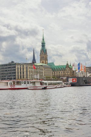 Foto de Editorial: HAMBURG, ALEMANIA, 31 DE MAYO DE 2022 - El Ayuntamiento de Hamburgo y el monumento a San Nicolás, visto desde el lago Binnenalster. La señal sobre el barco advierte de fuertes corrientes - Imagen libre de derechos