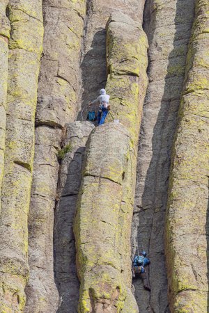 Photo for Editorial: DEVILS TOWER, CROOK COUNTY, WYOMING, UNITED STATES, SEPTEMBER 8, 2023 - Close up of two mountaineers ascending the Devils Tower, seen from the path around the mountain - Royalty Free Image